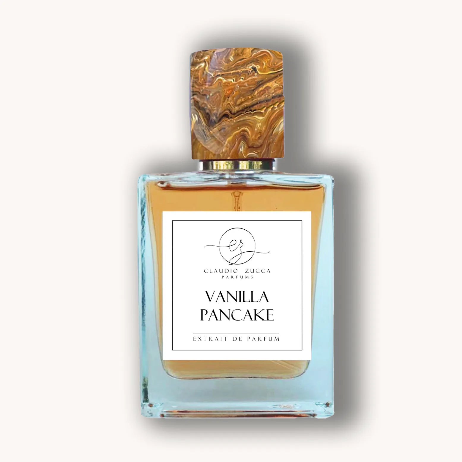 Alt text: A glass perfume bottle labeled "Claudio Zucca Vanilla Pancake," featuring a marbled wooden cap and a golden liquid inside, presented against a neutral background.