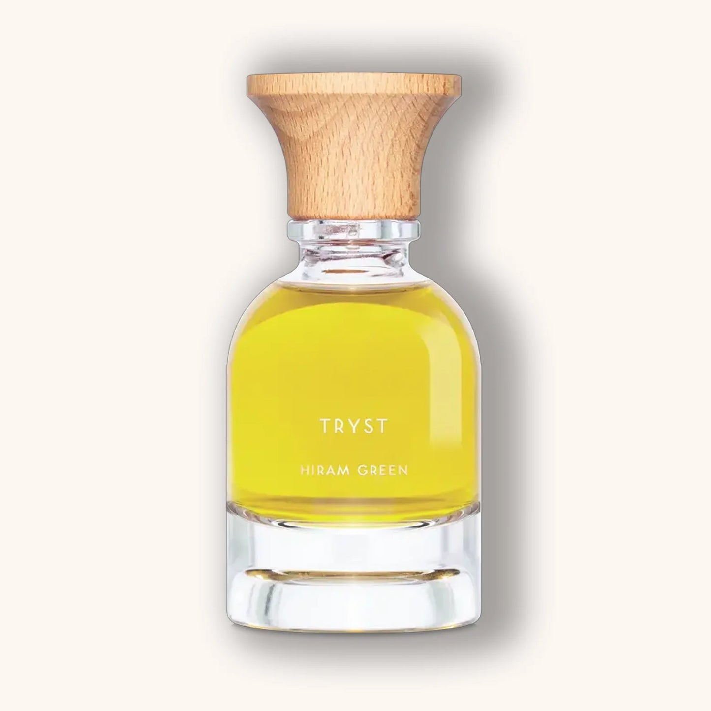 Hiram Green Tryst natural perfume in a clear bottle with bright yellow liquid and wooden cap.