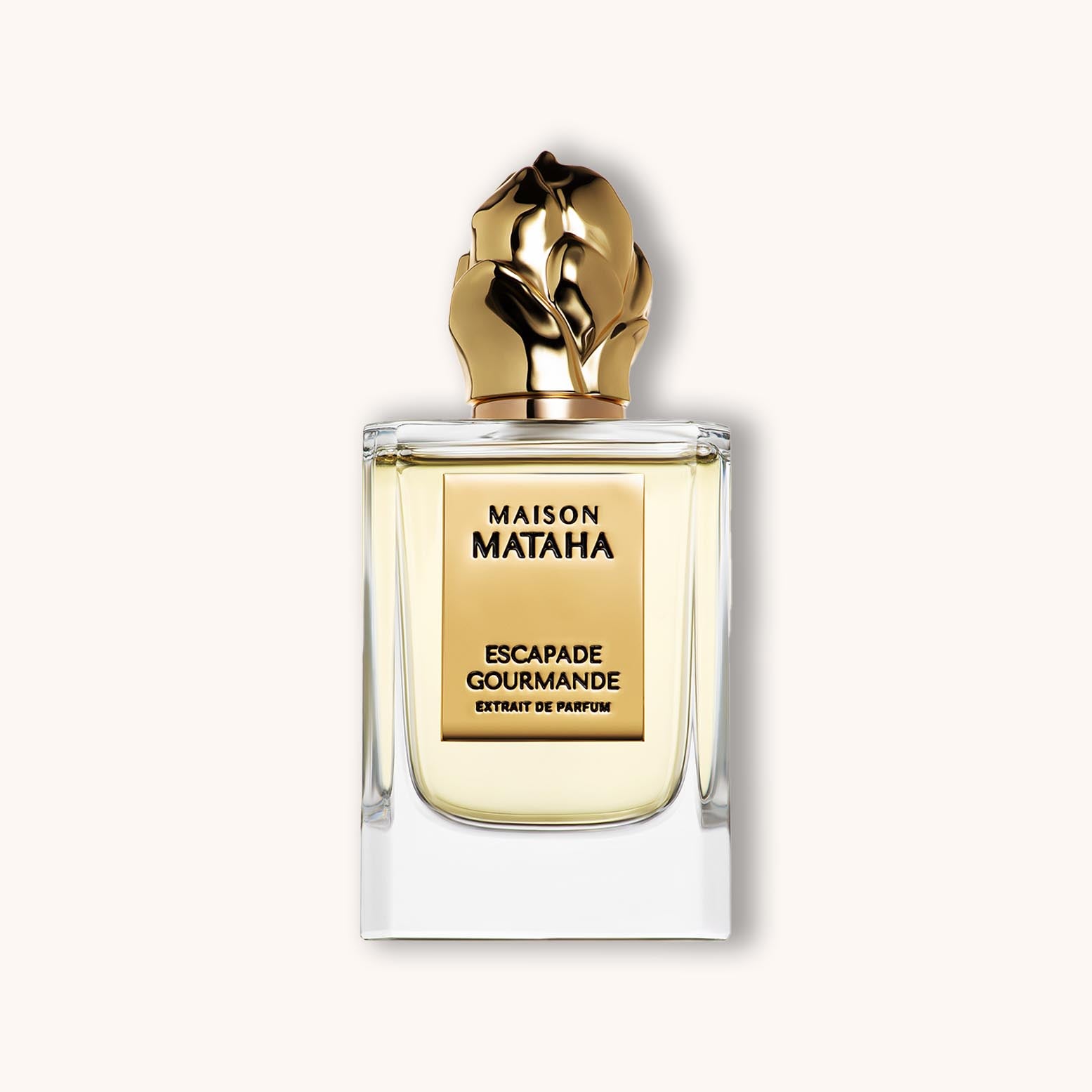 Alt text: A luxurious bottle of 'Maison Mataha Escapade Gourmande' perfume featuring a striking gold cap and a clear glass design, exuding elegance and sophistication.