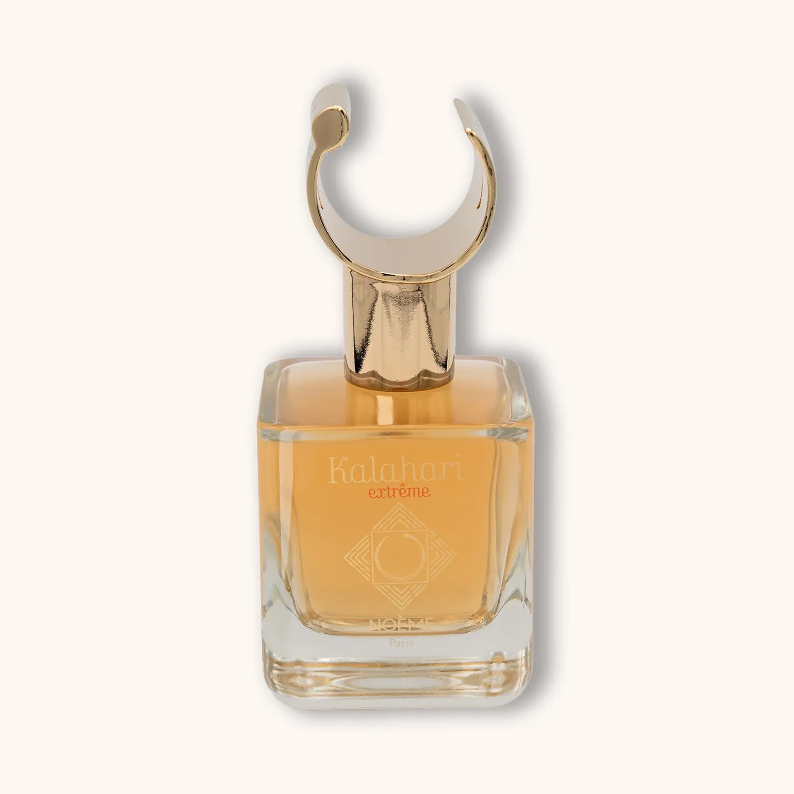 Alt text: A clear glass bottle of Noème Paris Kalahari Extreme perfume, featuring an elegant gold cap shaped like a crescent. The fragrance is a warm amber color, reflecting sophistication and allure.