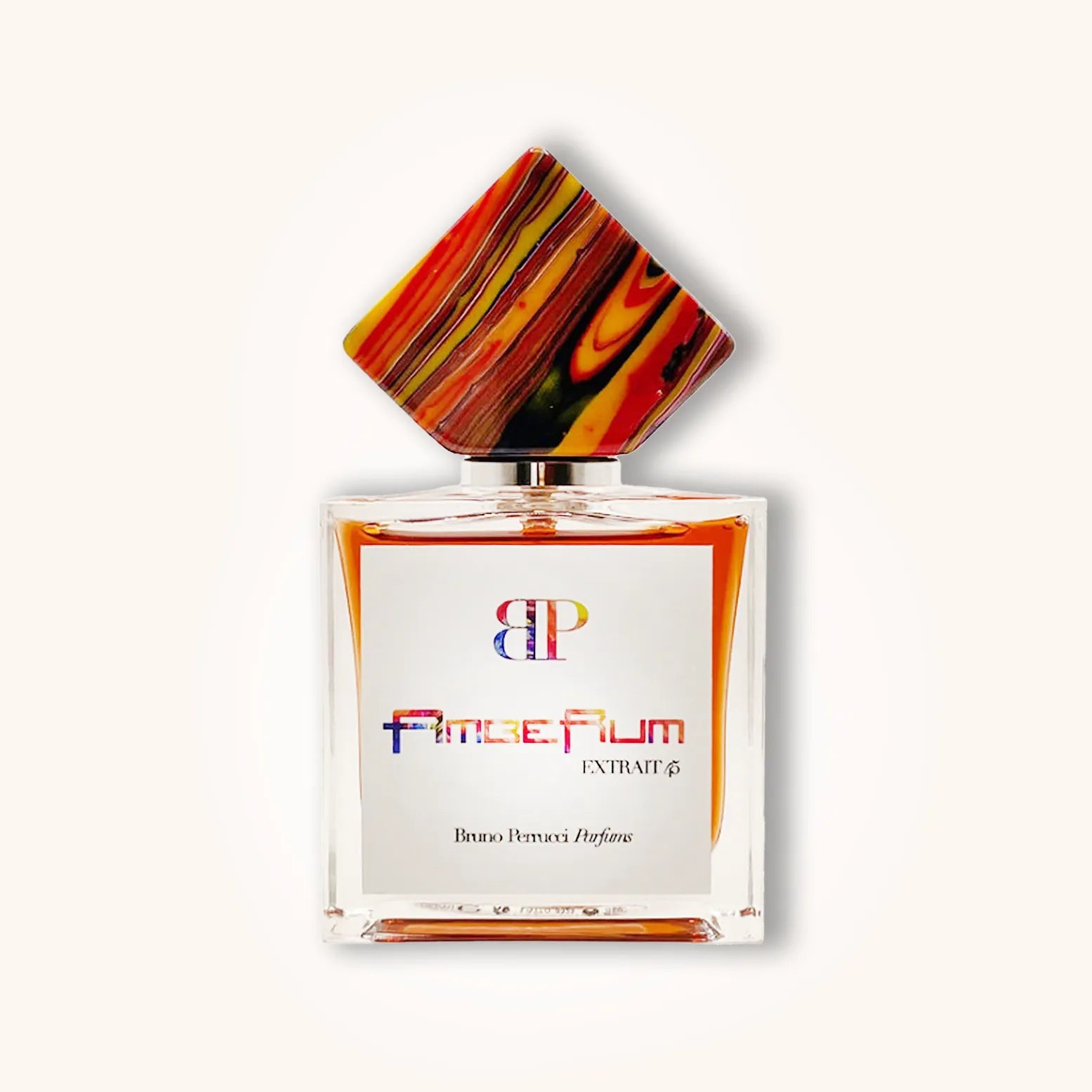 A stylish bottle of Bruno Perrucci AmbeRum, featuring a distinctive colorful geometric cap atop a clear glass container with a white label. The fragrance is presented as an extrait, showcasing an elegant and artistic design.