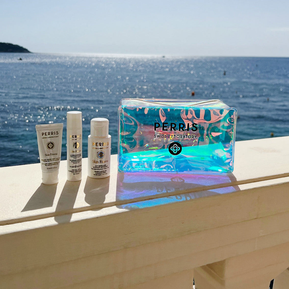 PerriS Swiss Laboratory cosmetic travel bag with skincare products on a ledge overlooking the ocean.