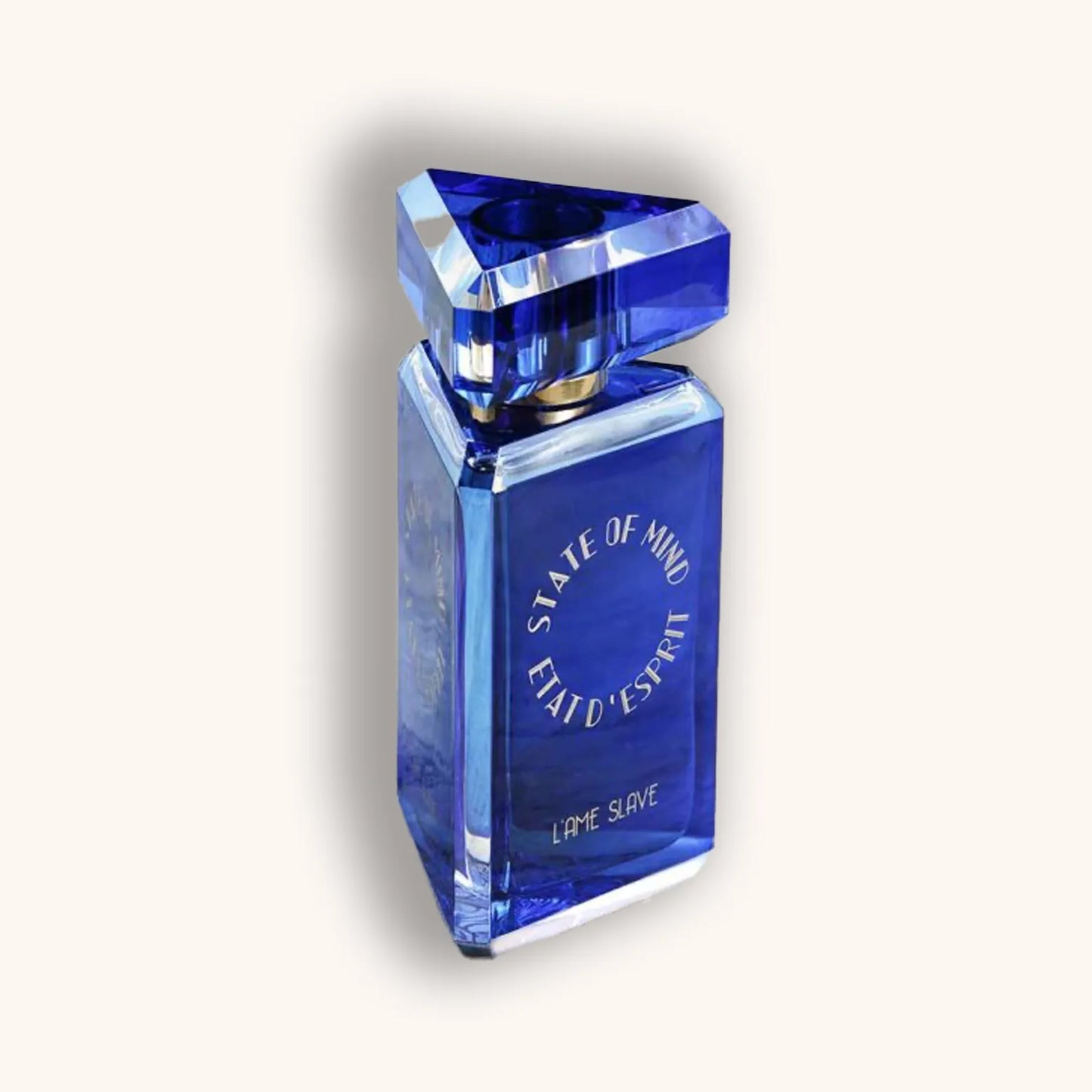 A striking blue fragrance bottle from the collection "State of Mind L’Ame Slave," featuring a geometric design and a crystal-like cap. The bottle showcases an elegant and contemporary aesthetic, perfect for a luxurious scent.