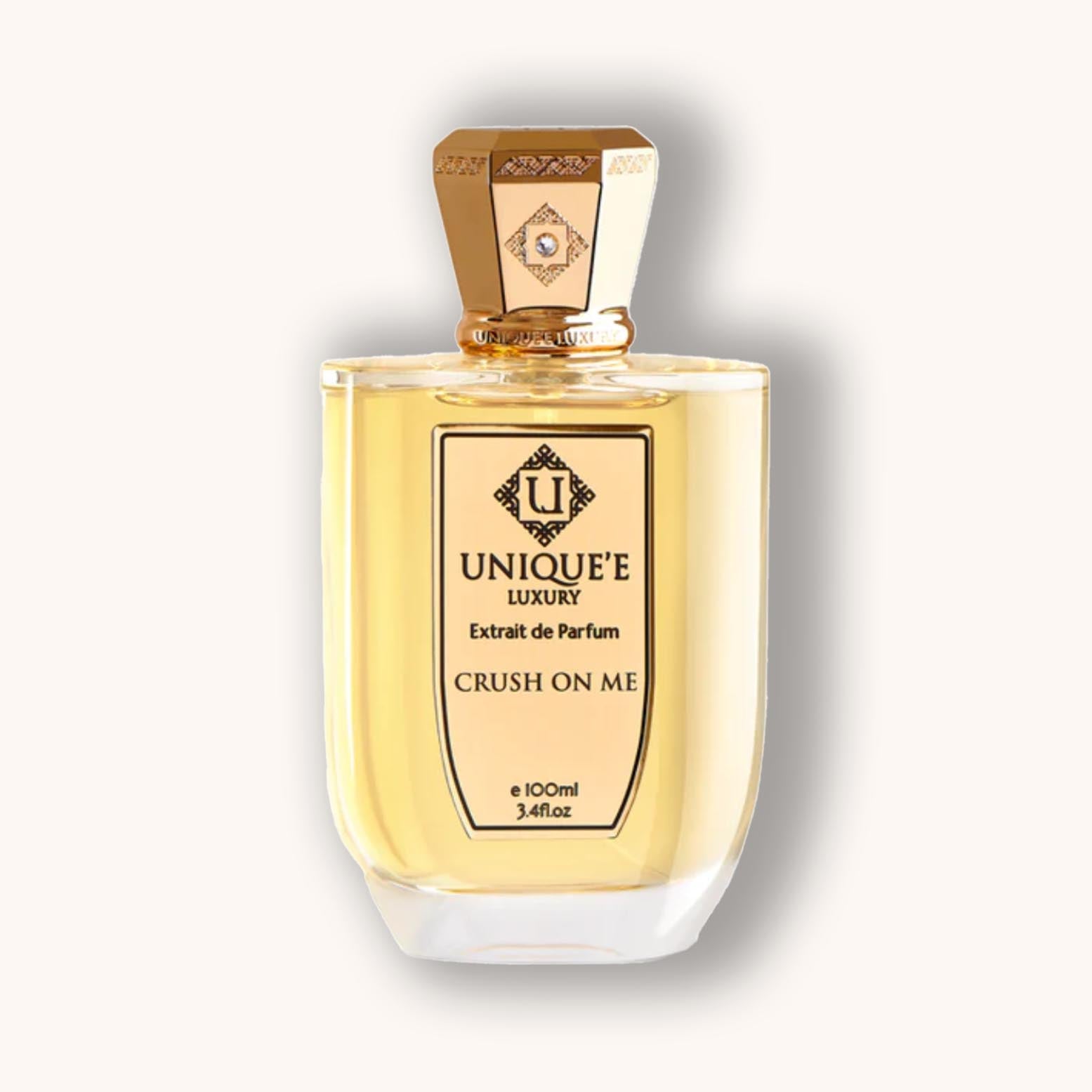 A bottle of Unique'e Luxury Crush on Me fragrance, featuring an elegant design with a gold cap and a clear glass container filled with golden-yellow perfume. The label prominently displays the brand name and product title.