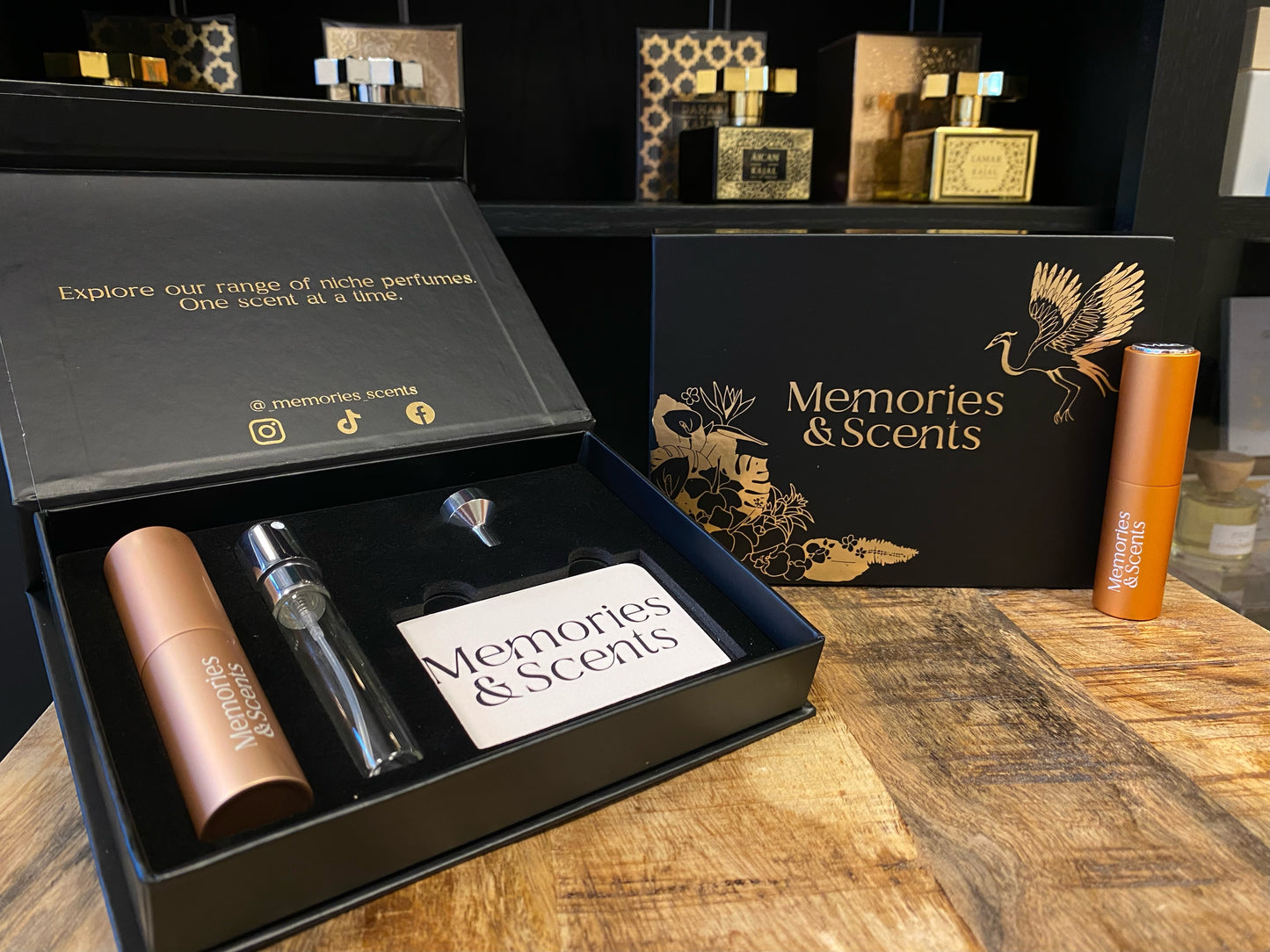 Alt text: "Open Memories & Scents Gift Box featuring niche perfumes, a travel spray, and an elegant design. The box is displayed on a wooden surface with a stylish background."