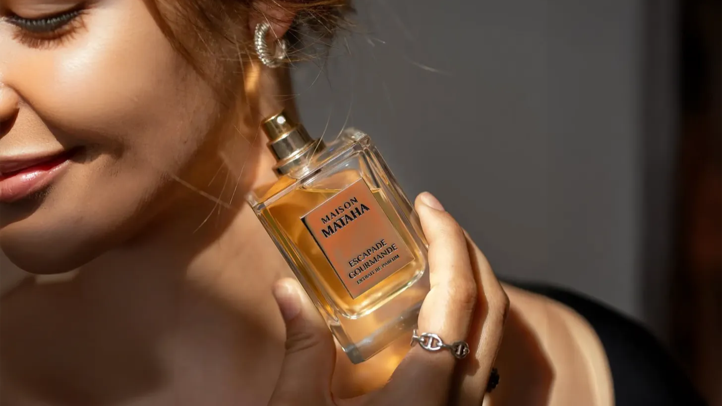 Woman holding a perfume bottle of Maison Mataha with a blurred background