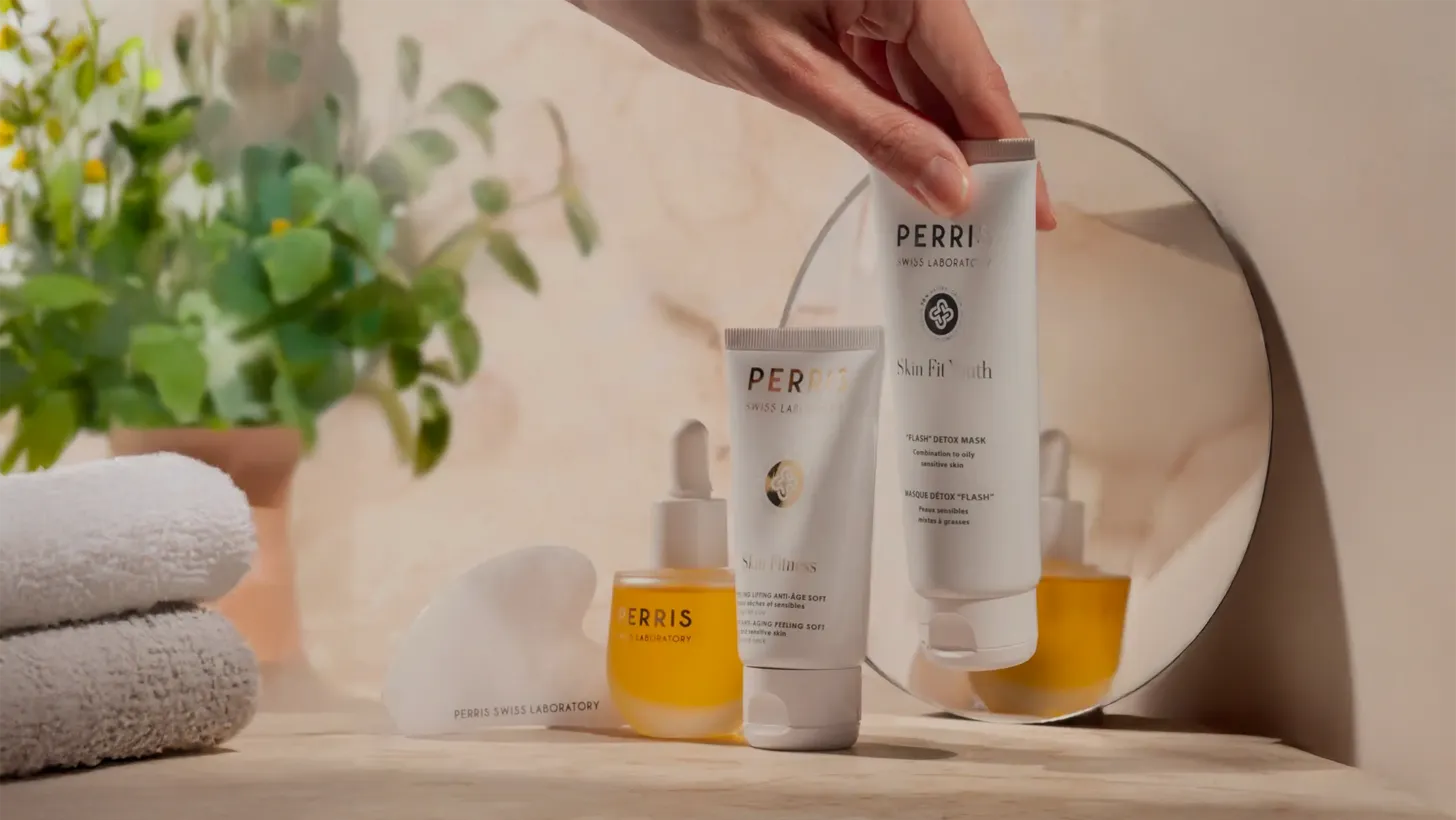 Perri skincare products on a wooden surface with a mirror and plant in the background