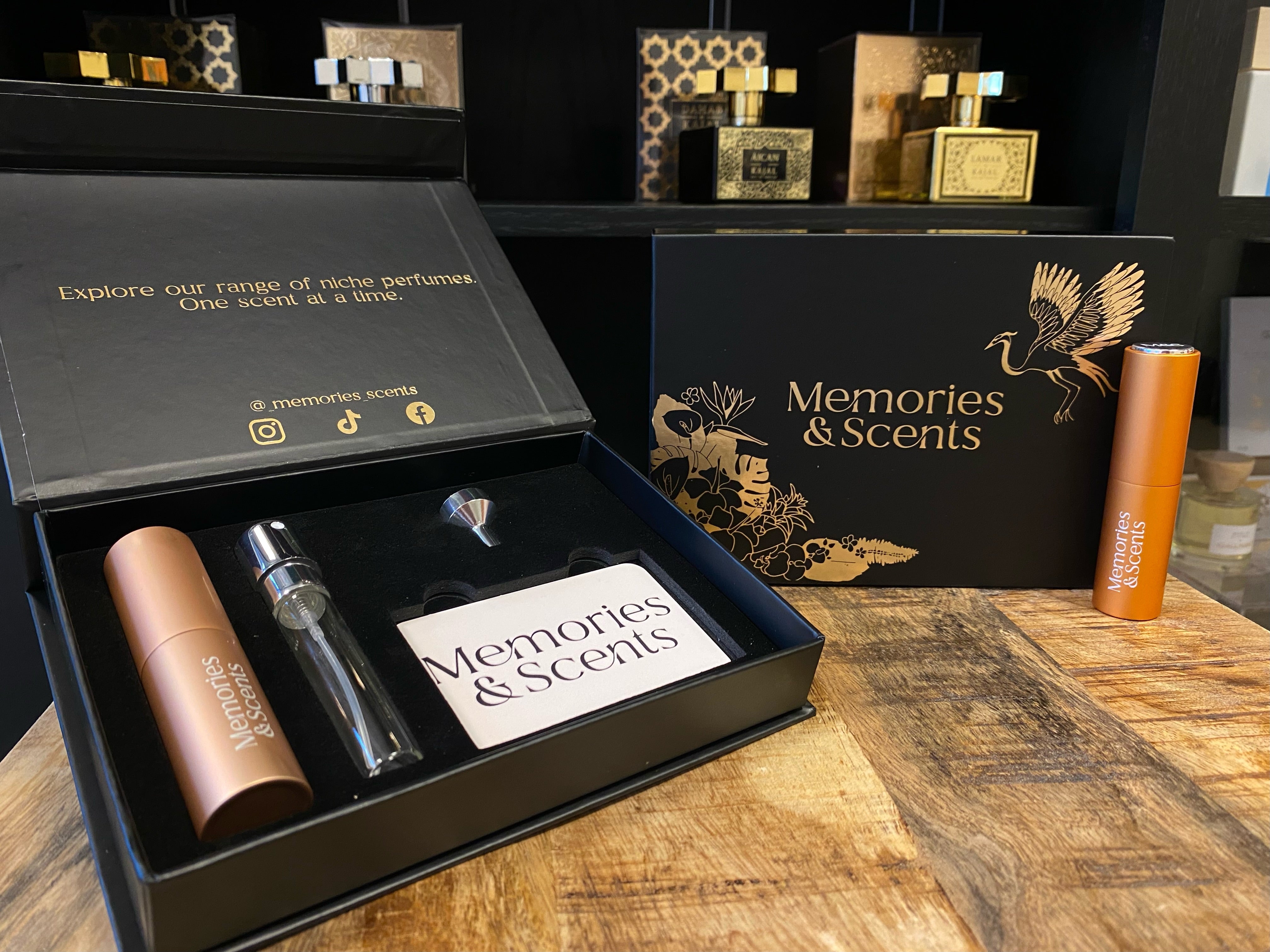 Alt text: "Open Memories & Scents Gift Box featuring niche perfumes, a travel spray, and an elegant design. The box is displayed on a wooden surface with a stylish background."
